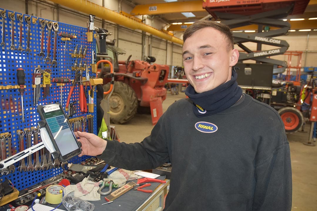 bild på en verkstad där en leende person trycker på en terminal