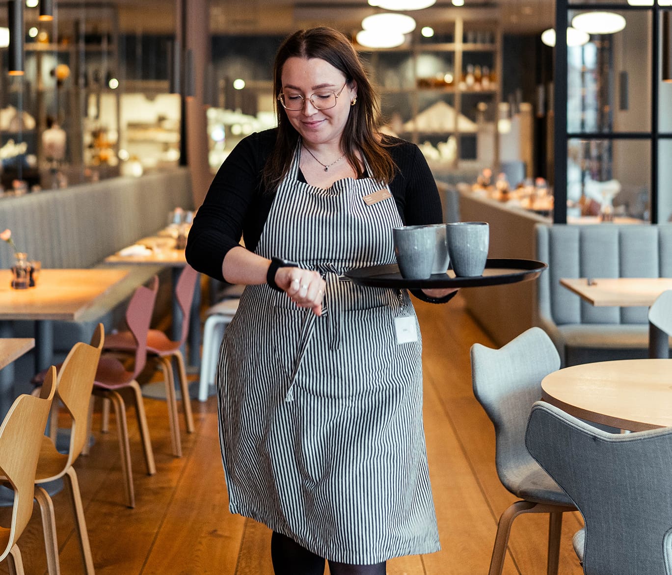 bild av en servitör som tittar på sin solcellssökarklocka med en tallrik med tre koppar kaffe