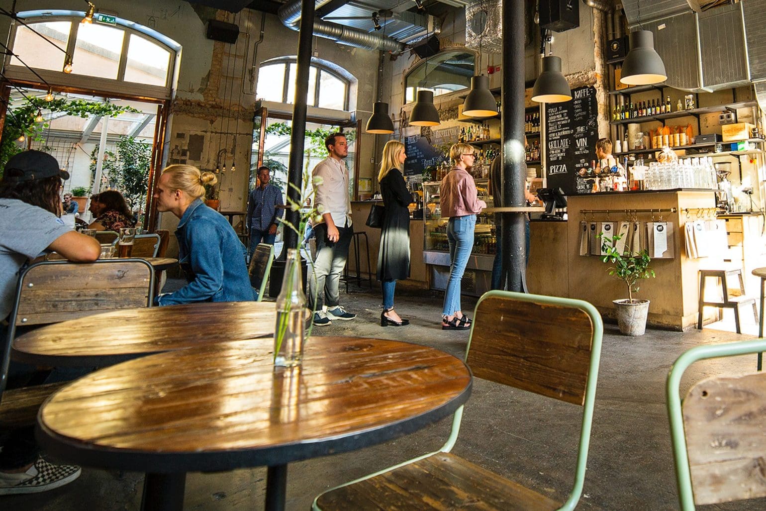 bild på ett kafé där några står i kö och andra sitter och njuter av sina drinkar