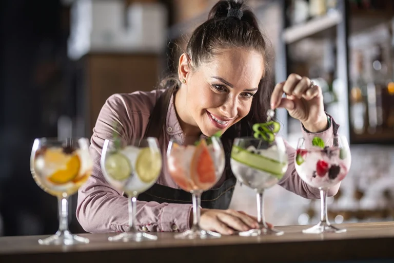 Servitris gör i ordning fem färgglada cocktails – restaurangmiljö med fokus på service och gästupplevelse